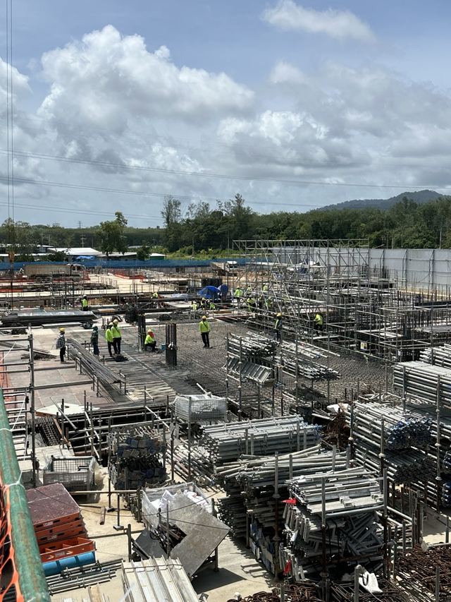 Workers laying reinforcement mesh beside stacked scaffolding materials
